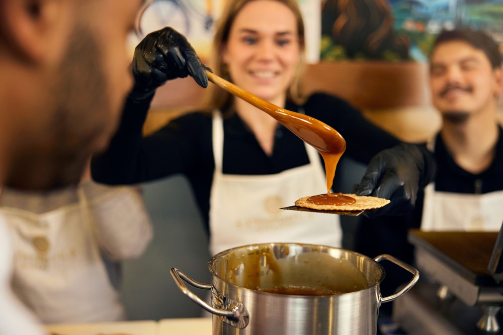 Pouring caramel onto a freshly made stroopwafel during a workshop
